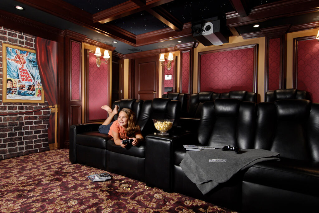 Child playing video games in a home theater with recliner seating, popcorn, projector, and classic cinema decor